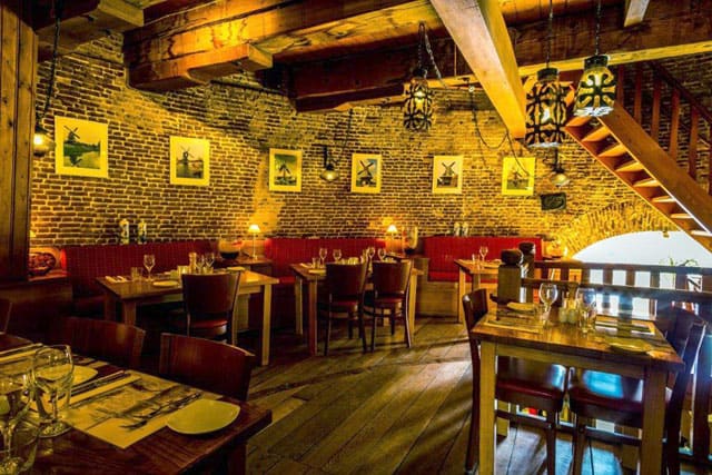 Gedekte tafels in de eetzaal van De Noordmolen, met molenfoto's aan de muur